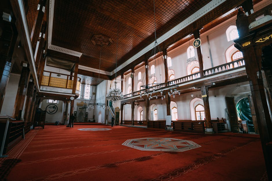 Spacious Turkish mosque interior showcasing intricate design, chandeliers, and red carpets.