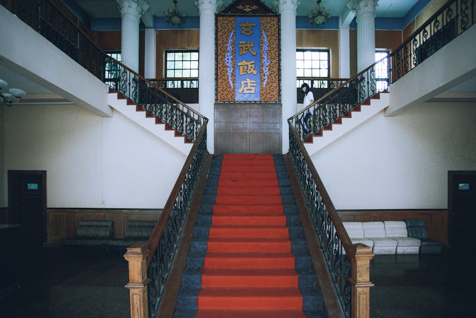 A classic red-carpeted staircase in a vintage interior with ornate details and elegant furnishings.