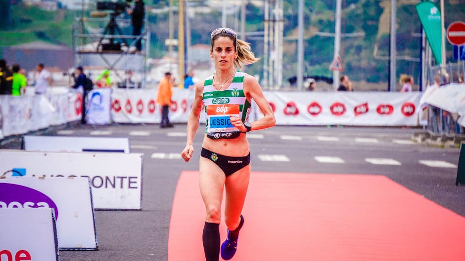 Focused female athlete crossing the finish line during an outdoor marathon race.